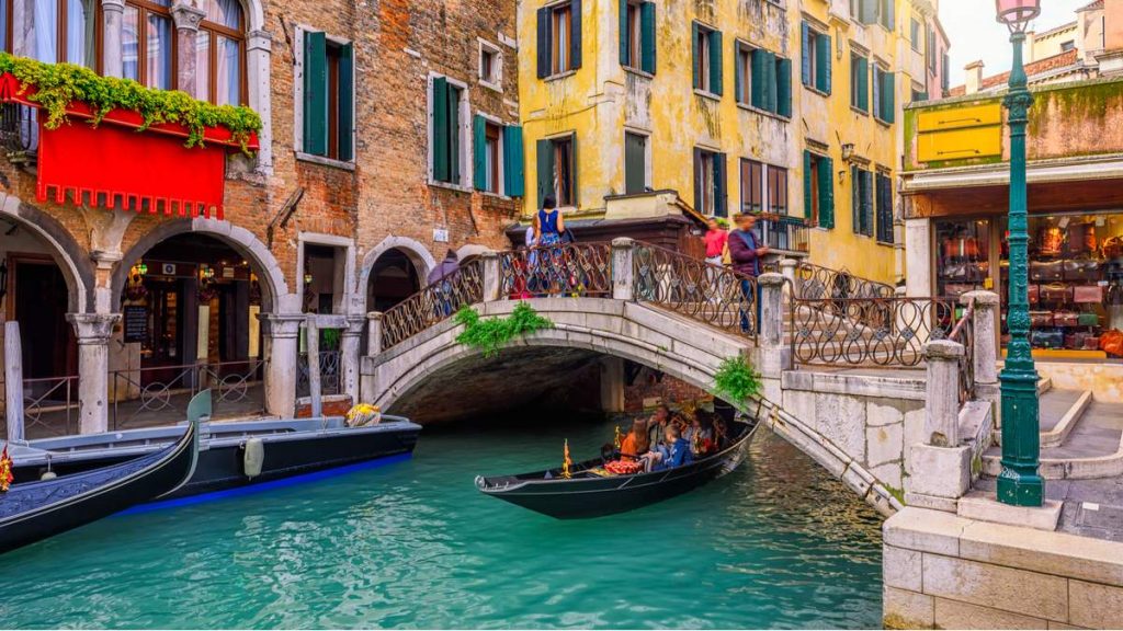 Canal estreito, com gôndola e ponte em Veneza, Itália.