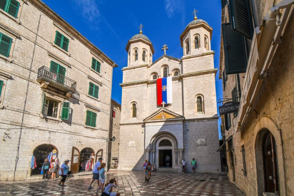 Turistas na frente da Igreja Nicholas, uma Igreja Ortodoxa Sérvia no centro da cidade velha de Kotor, Montenegro.